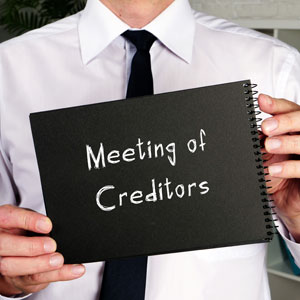 Man holding a sign about a Meeting of Creditors during a creditor negotiation process.