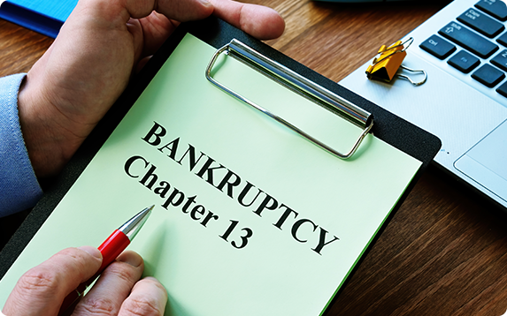 Clipboard with Chapter 13 bankruptcy document on a desk, representing financial debt solutions.