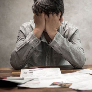Man stressed by bills on table