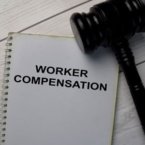 Worker compensation file and gavel on desk representing legal claims for workplace injuries