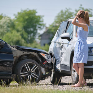 Two-car accident scene with damaged vehicles and distressed female driver