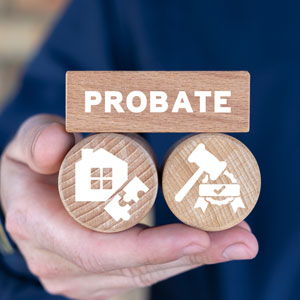 Probate process: hand holding wooden blocks with house and gavel symbols.  