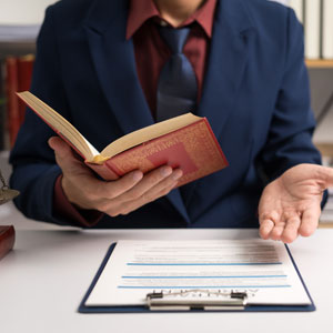 Man holding an open red book in an office setting.